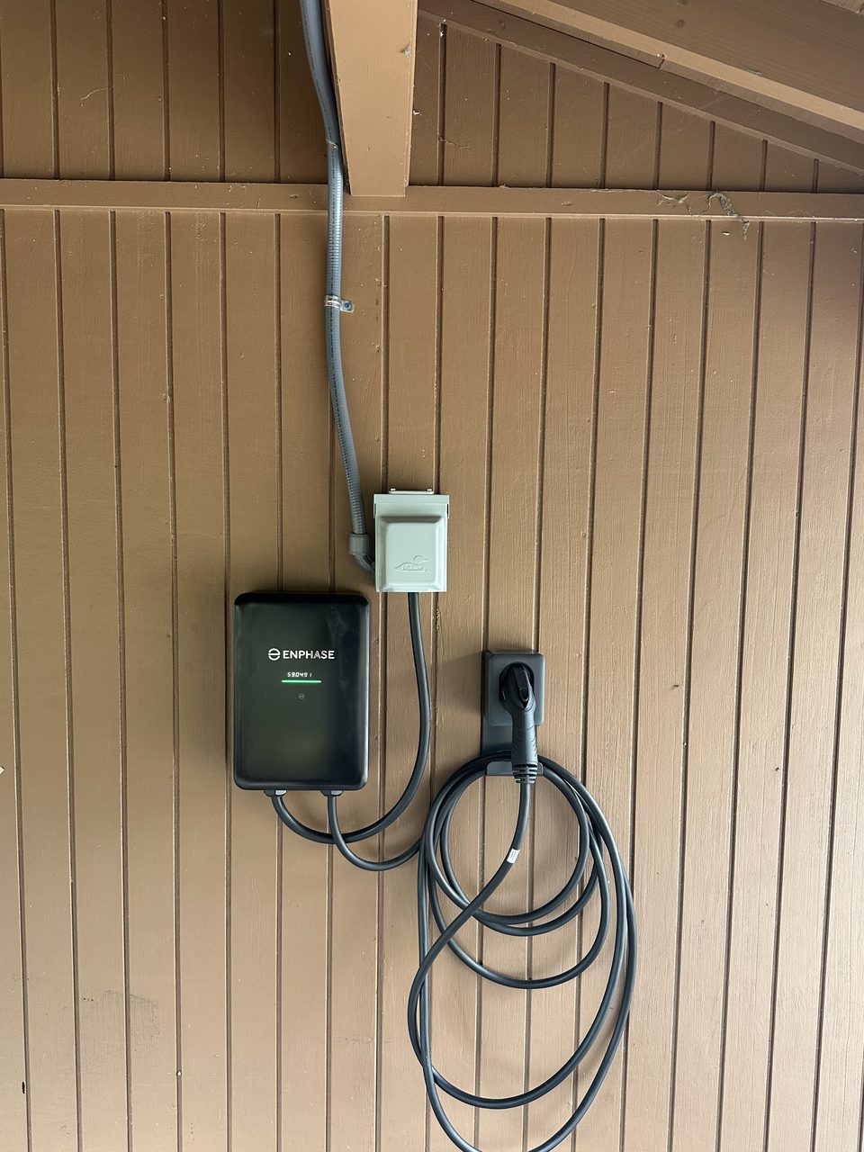 Enphase EV charger powered on with its cable coiled on the holster